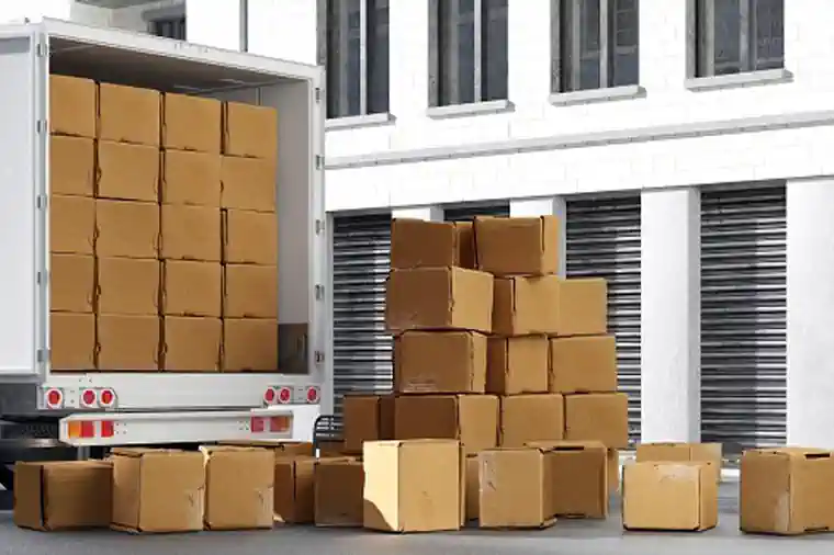 Gestapelte Kisten vor Lastwagen vor Lagerhalle bei Einlagerung